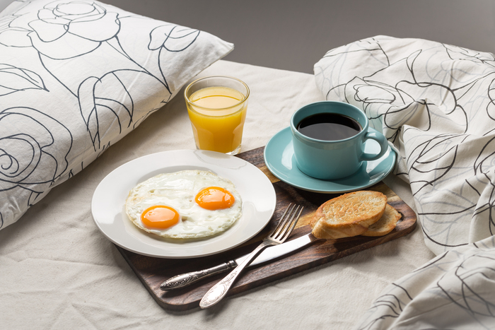 um café da manhã na cama simples, com ovo, café, suco e torrada.