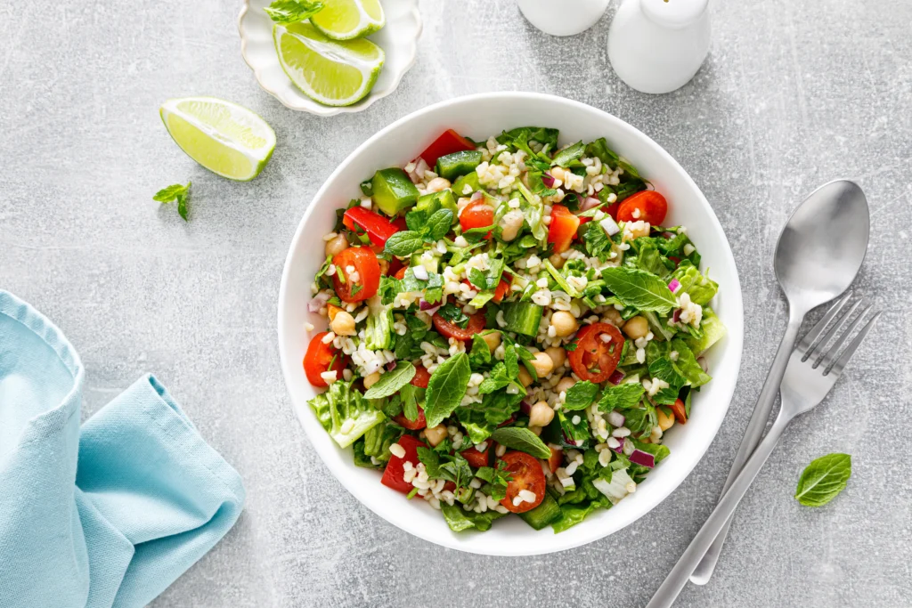 Salada fresca com grão-de-bico, hortelã, tomate, pimentão verde e vermelho, arroz ou trigo e folhas verdes, servida com limão