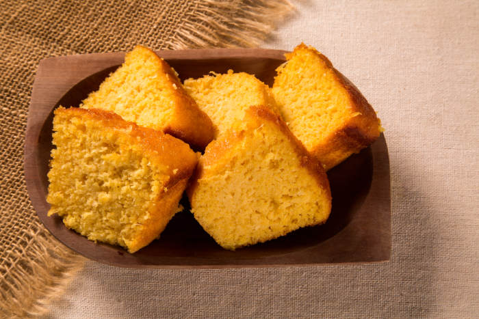 Fatias de bolo de milho cremoso servidas em prato de madeira sobre tecido rústico